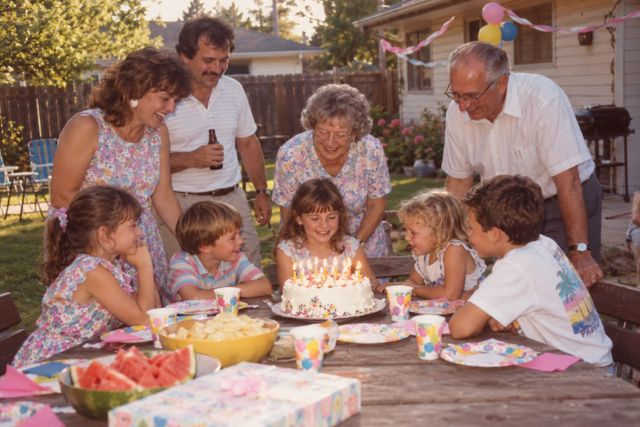 Paper streamers, a homemade cake, and a crowded picnic table on a bright summer afternoon.