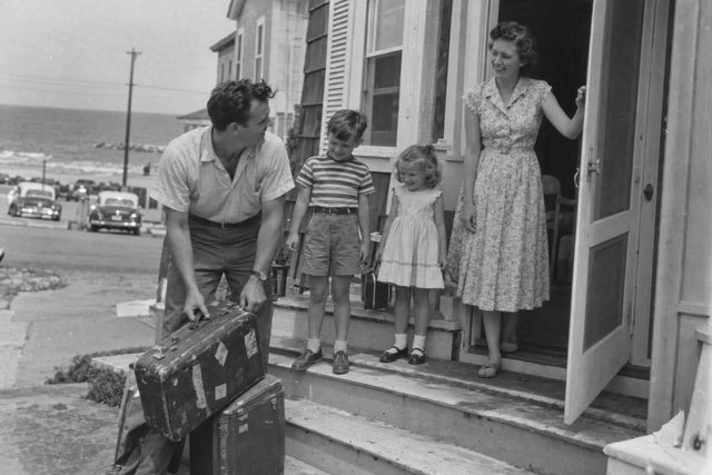 A seaside boarding-house arrival, with everyone dressed for the journey and far too much luggage.