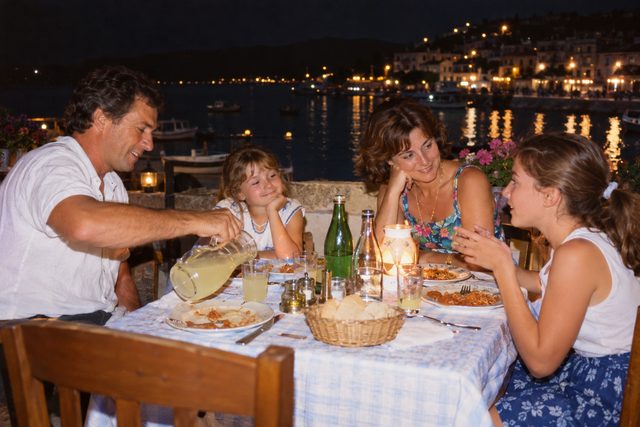 A seaside terrace dinner, caught in the glow of table lamps and camera flash.