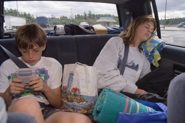The back seat on the way home: one handheld game, one sleeping passenger, and a heap of towels.